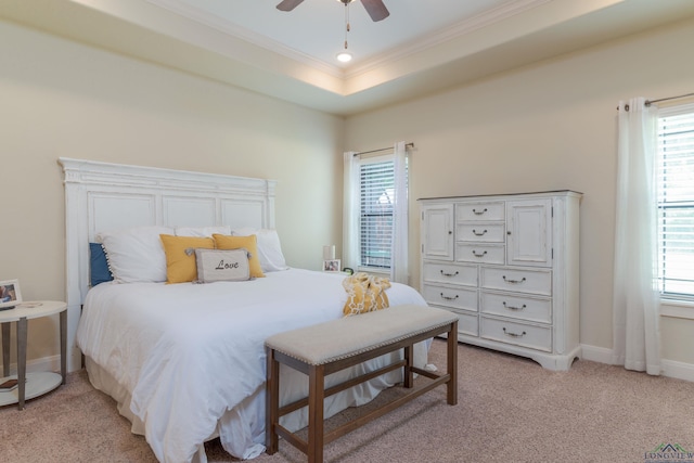 carpeted bedroom featuring a tray ceiling, multiple windows, and ceiling fan