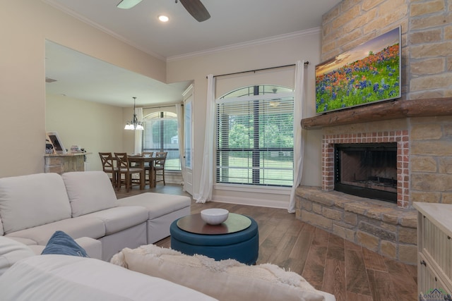 living room featuring a fireplace, ceiling fan with notable chandelier, dark hardwood / wood-style floors, and ornamental molding