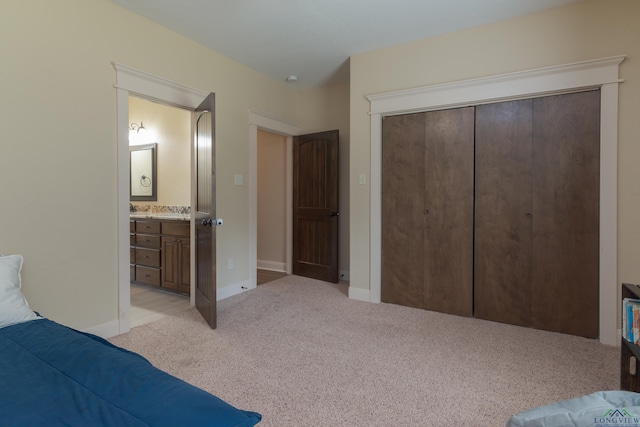 bedroom with ensuite bath, light carpet, and a closet