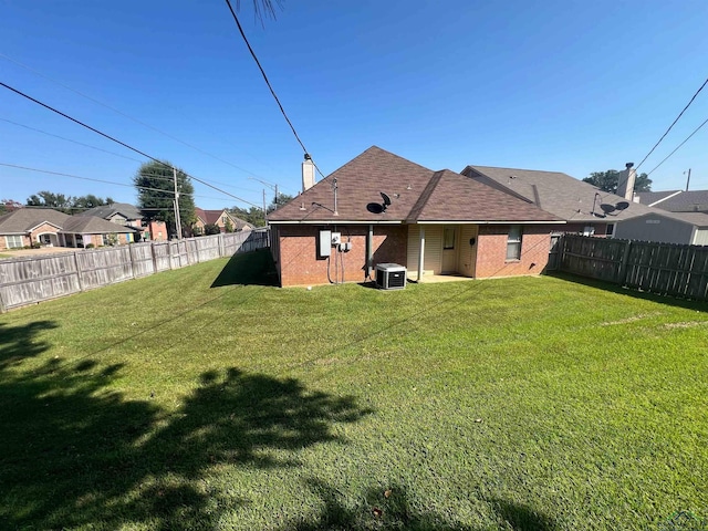 rear view of house with a yard and central AC