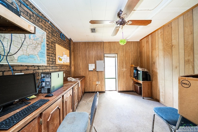 office area featuring light carpet, wooden walls, visible vents, and a ceiling fan