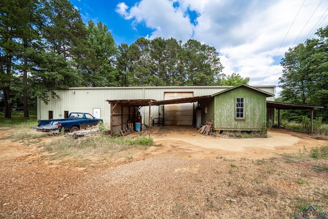 exterior space with a garage, a pole building, an outdoor structure, and dirt driveway