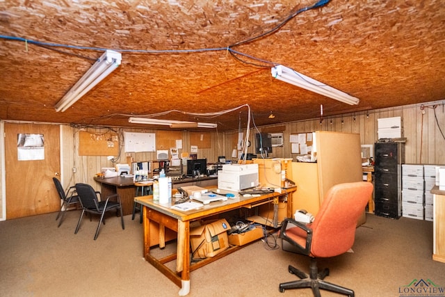 home office with wood walls, a workshop area, and light colored carpet