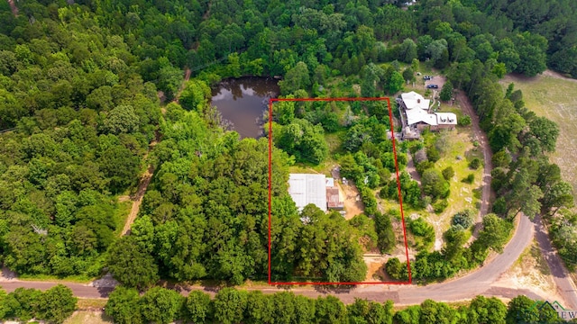 birds eye view of property featuring a water view and a wooded view