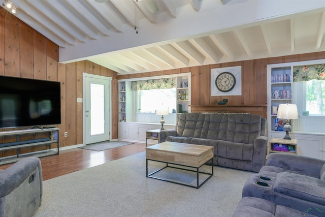 living room featuring lofted ceiling with beams, wood-type flooring, wooden walls, and built in shelves