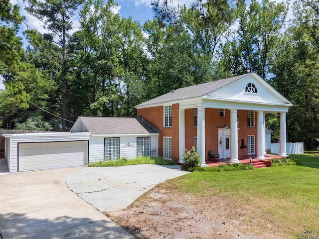 neoclassical home featuring a porch, a front yard, and a garage