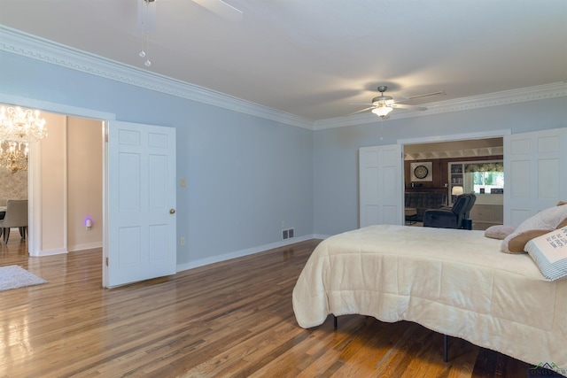 bedroom featuring hardwood / wood-style floors, ceiling fan with notable chandelier, and ornamental molding