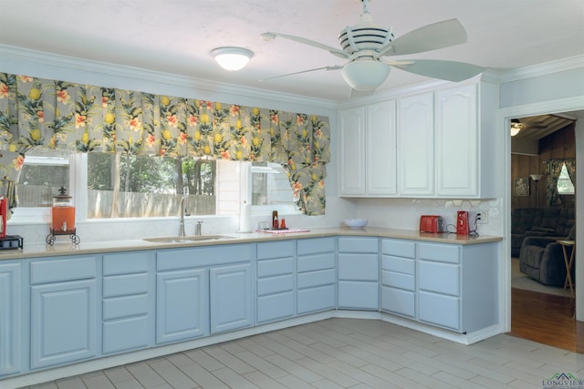 kitchen with white cabinets, ceiling fan, crown molding, and sink