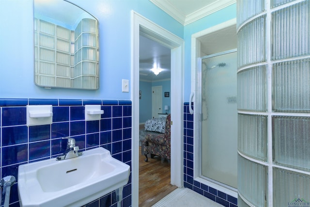 bathroom featuring an enclosed shower, ornamental molding, sink, and tile walls