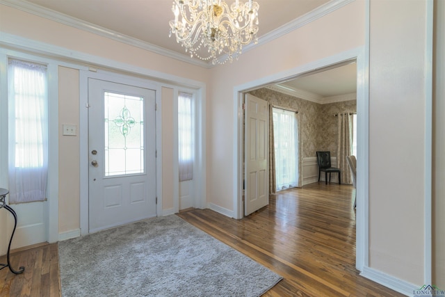 entryway with dark wood-type flooring, crown molding, and a chandelier