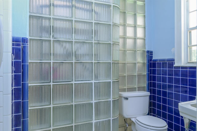 bathroom featuring toilet and tile walls