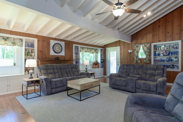 living room with wood walls, ceiling fan, a healthy amount of sunlight, and hardwood / wood-style flooring