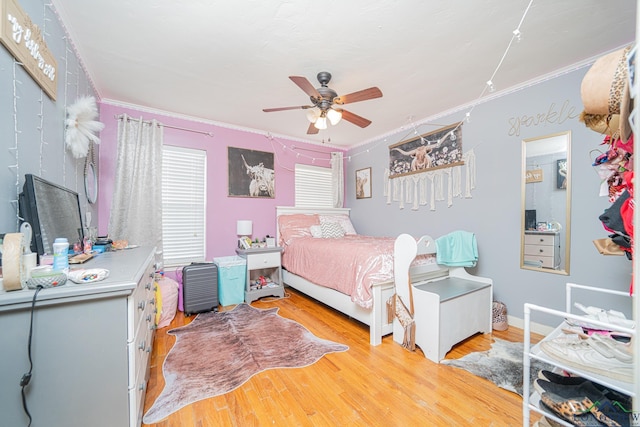 bedroom featuring baseboards, light wood-style flooring, ornamental molding, and a ceiling fan