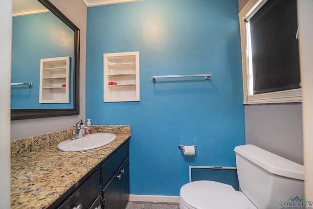 half bathroom featuring toilet, baseboards, and vanity