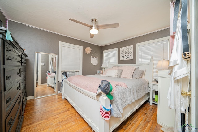 bedroom with ornamental molding, cooling unit, light wood-style flooring, and a ceiling fan