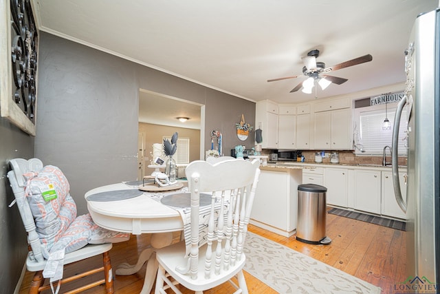 dining room featuring light wood-type flooring, crown molding, and ceiling fan