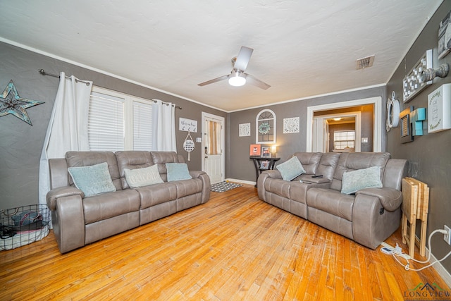 living room featuring ceiling fan, wood finished floors, visible vents, and crown molding