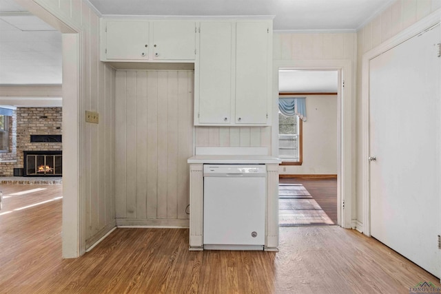 kitchen featuring a fireplace, crown molding, dishwasher, and light hardwood / wood-style floors