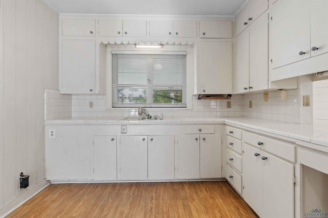 kitchen featuring decorative backsplash, sink, white cabinets, and light wood-type flooring