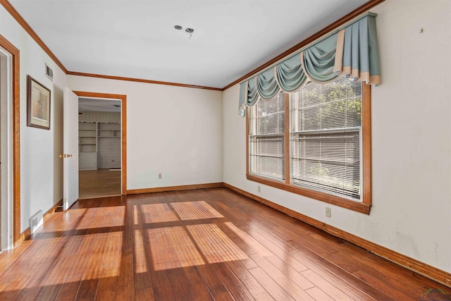 spare room featuring built in shelves, ornamental molding, and hardwood / wood-style flooring