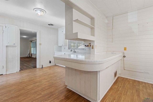 kitchen featuring kitchen peninsula, tile countertops, white cabinetry, and light hardwood / wood-style flooring