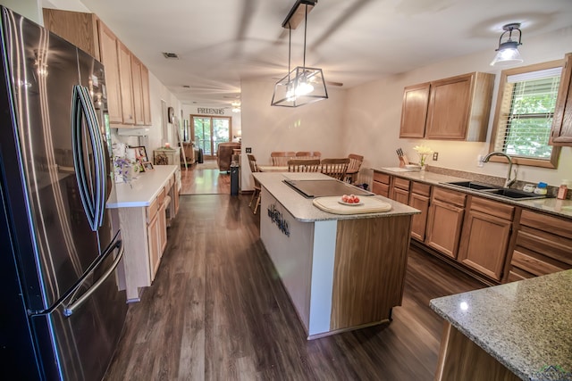 kitchen featuring a center island, sink, dark hardwood / wood-style floors, stainless steel fridge, and decorative light fixtures