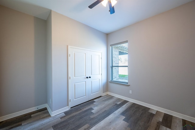 unfurnished bedroom with a closet, ceiling fan, and dark wood-type flooring