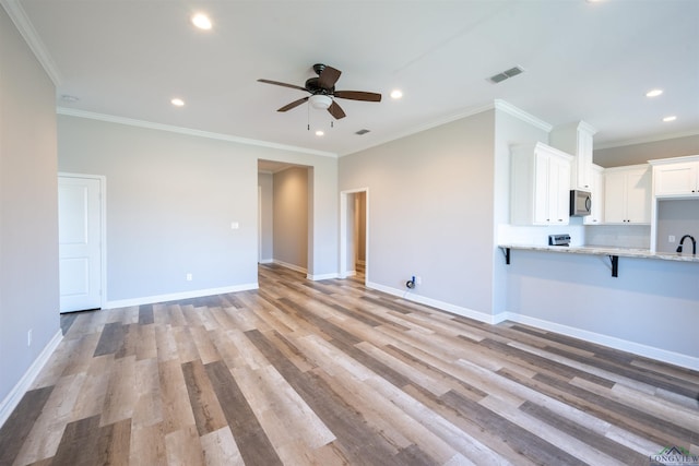 unfurnished living room featuring crown molding, sink, ceiling fan, and light wood-type flooring