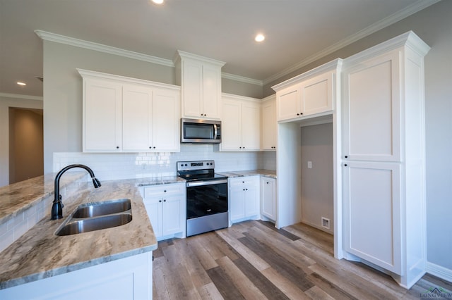 kitchen with backsplash, sink, white cabinetry, kitchen peninsula, and stainless steel appliances