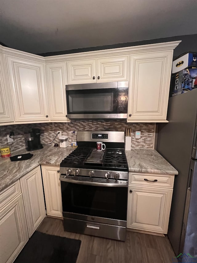 kitchen with dark wood-type flooring, stainless steel appliances, tasteful backsplash, light stone counters, and white cabinets