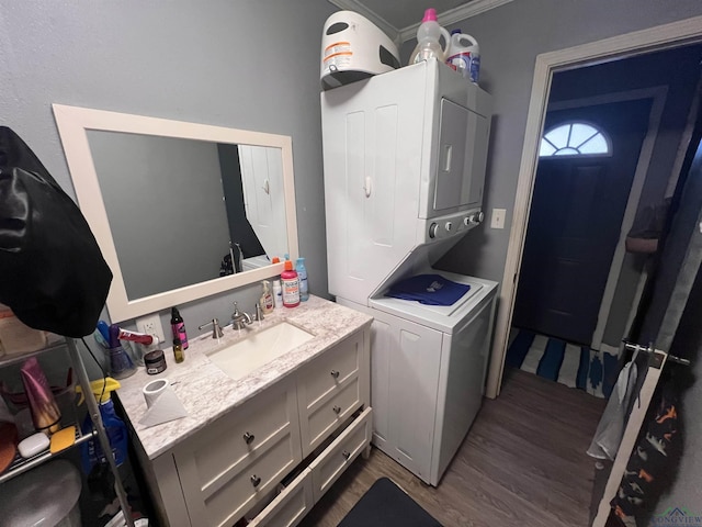 laundry room featuring ornamental molding, stacked washer / dryer, dark hardwood / wood-style flooring, and sink