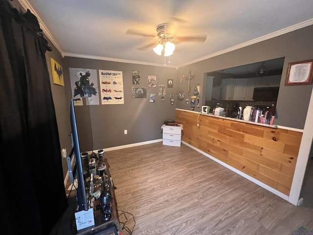 interior space featuring wood-type flooring, ceiling fan, and crown molding