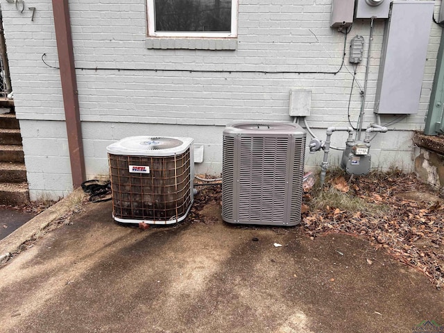 exterior details featuring electric meter, brick siding, gas meter, and cooling unit