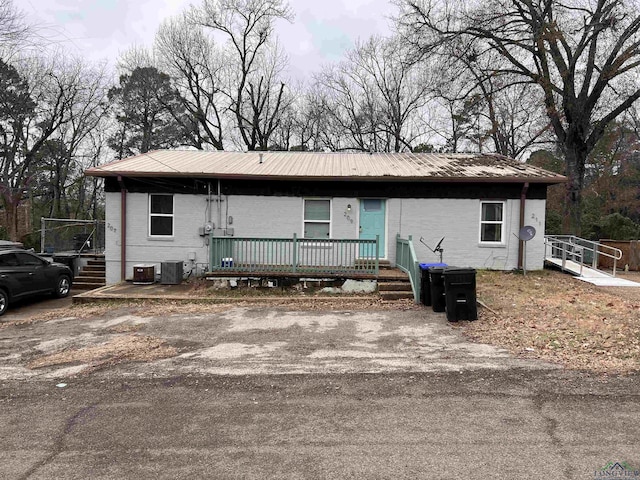 single story home with central air condition unit, metal roof, and brick siding