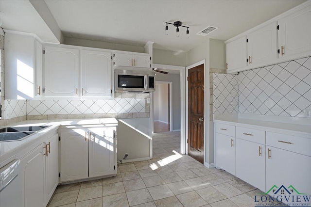 kitchen featuring white dishwasher, tasteful backsplash, white cabinets, and light tile patterned flooring