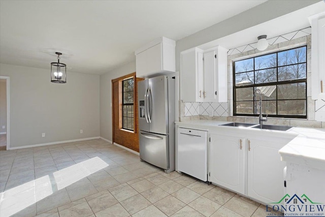 kitchen featuring stainless steel refrigerator with ice dispenser, sink, dishwasher, pendant lighting, and white cabinets