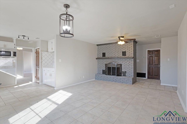 unfurnished living room with ceiling fan, a brick fireplace, and light tile patterned floors