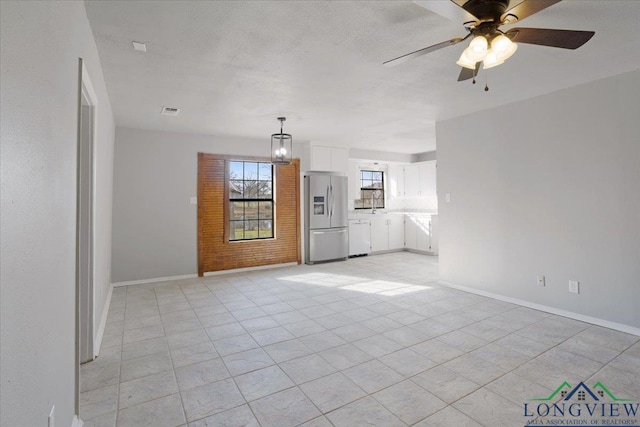 unfurnished living room with ceiling fan and a textured ceiling