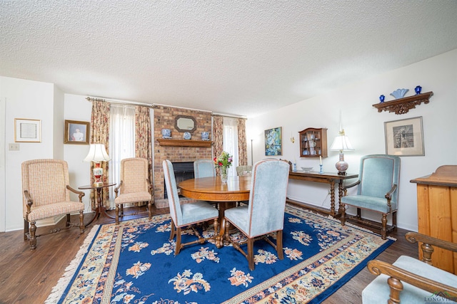 dining room featuring a textured ceiling, dark hardwood / wood-style floors, and a brick fireplace