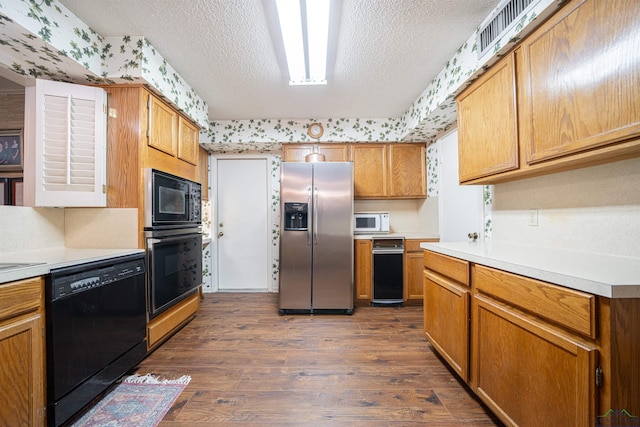 kitchen with dark hardwood / wood-style floors, black appliances, and a textured ceiling