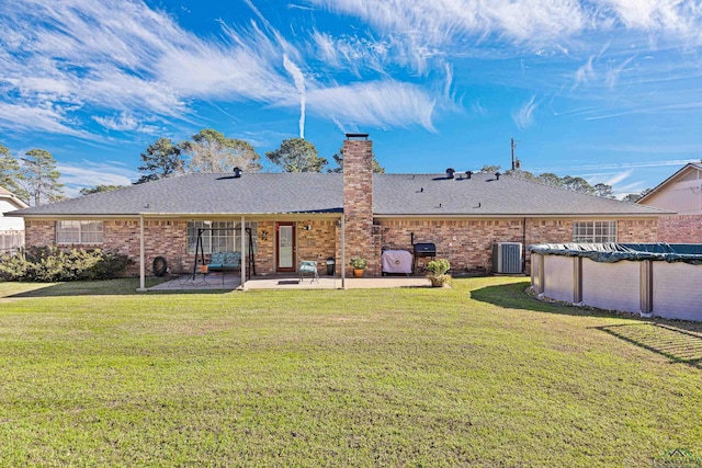 rear view of property with central air condition unit, a yard, a patio, and a covered pool