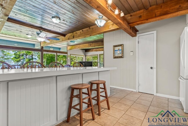 620 Shadywood Ln, Avinger, TX 75630 - kitchen featuring light tile patterned flooring, a ceiling fan, a wood ceiling with exposed beams, freestanding refrigerator, and a kitchen breakfast bar