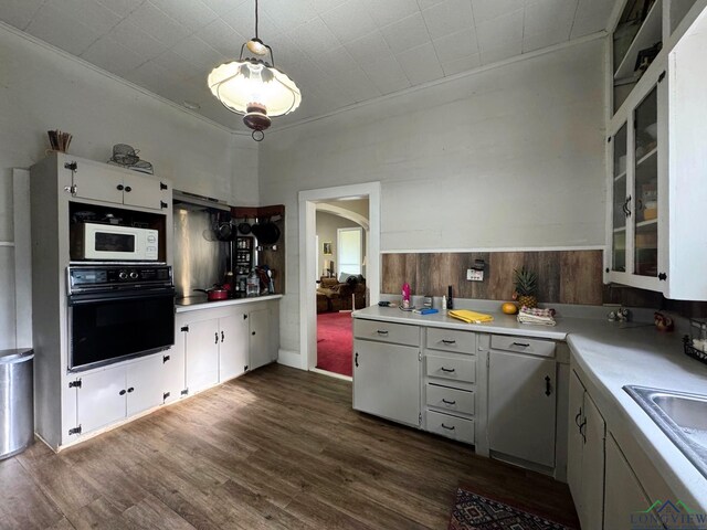 123 E 12th St, Mount Pleasant, TX 75455 - kitchen featuring black oven, white microwave, arched walkways, light countertops, and dark wood-type flooring