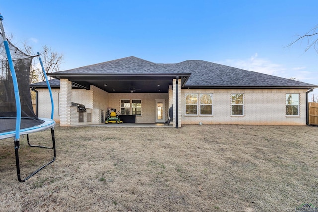 rear view of property with ceiling fan and a trampoline