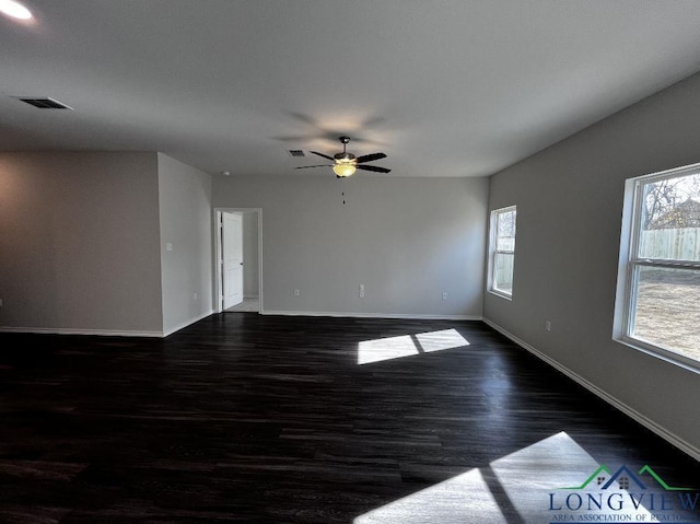 empty room with a healthy amount of sunlight, dark wood-type flooring, and ceiling fan