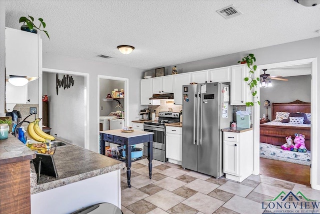 kitchen with ceiling fan, decorative backsplash, appliances with stainless steel finishes, white cabinetry, and washing machine and clothes dryer