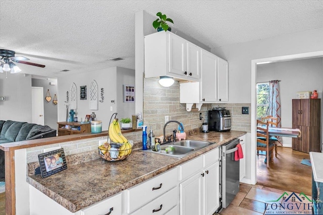 kitchen with dishwasher, sink, decorative backsplash, a textured ceiling, and white cabinetry