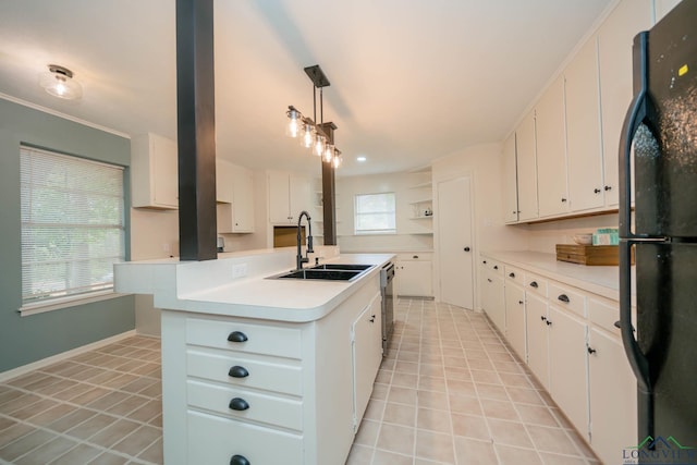 kitchen with black refrigerator, a kitchen island with sink, sink, pendant lighting, and white cabinetry