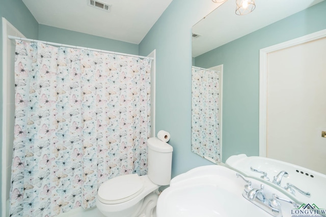 bathroom featuring curtained shower, sink, and toilet