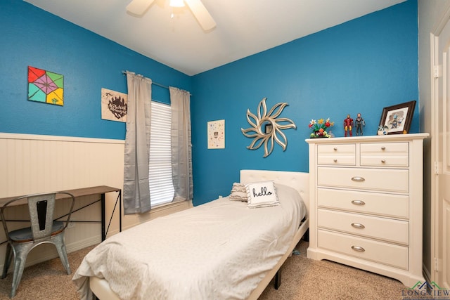 bedroom featuring light carpet, a wainscoted wall, and ceiling fan